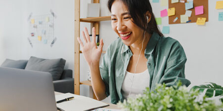 Woman waving from home office on her laptop connecting with her comprehensive EAP via video telehealth.